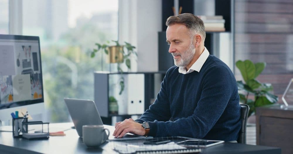 Person writing an introduction email on a laptop in an office